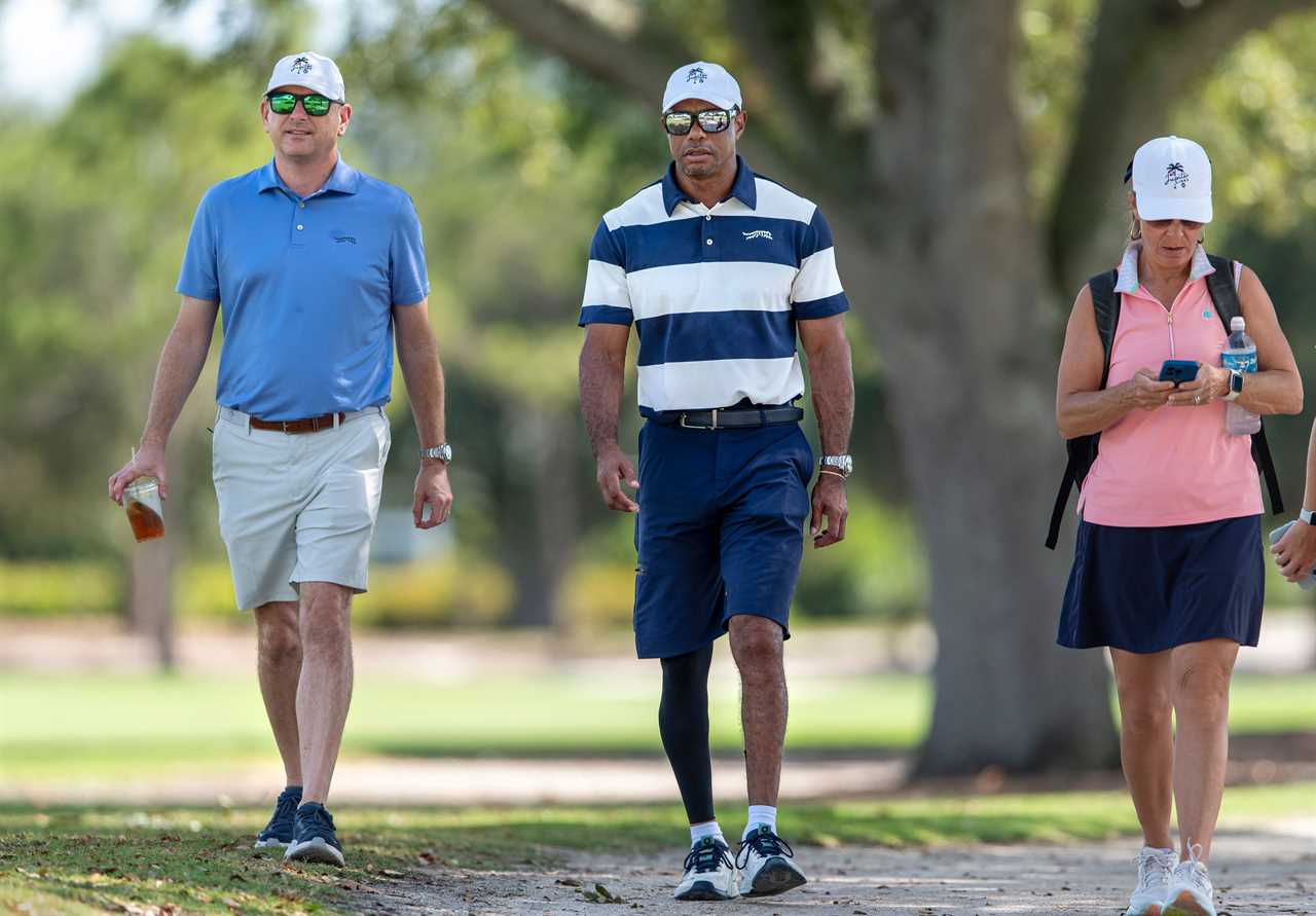 Tiger Woods walking a golf course with two other people.