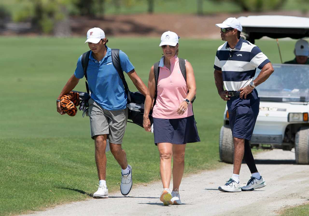 Charlie Woods walking with his father, Tiger Woods, and another person on a golf course.