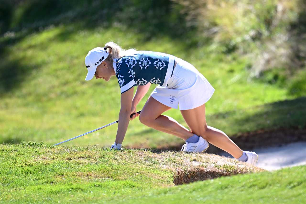 Golfer Charley Hull falling while climbing out of a bunker.