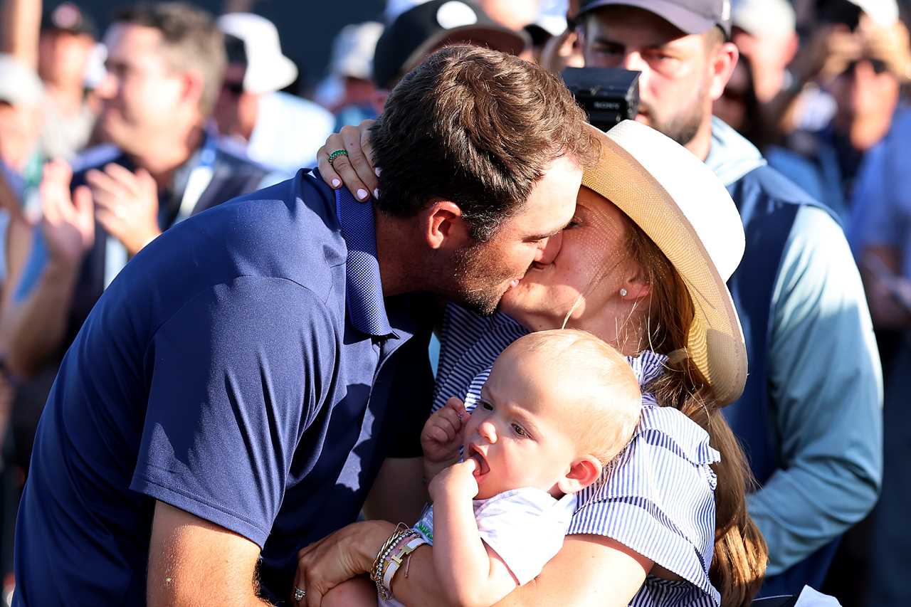 Scottie Scheffler kisses his wife while holding their baby.