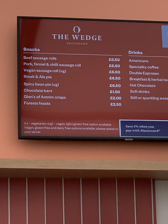 The Wedge Delicatessen menu board showing snacks and drinks with prices.