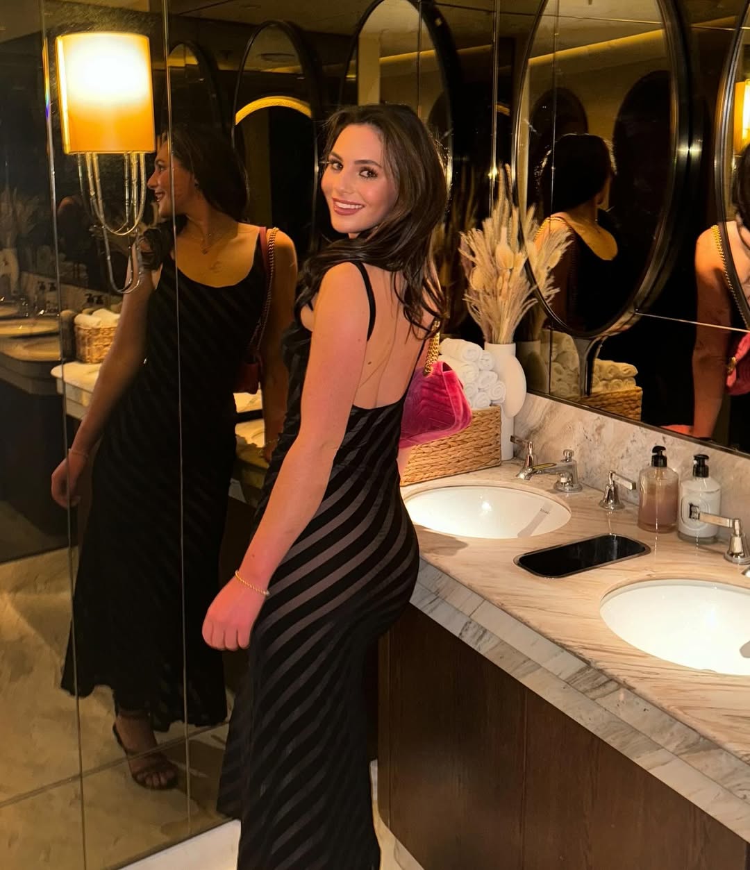 Woman in a black and white striped dress in a restroom.