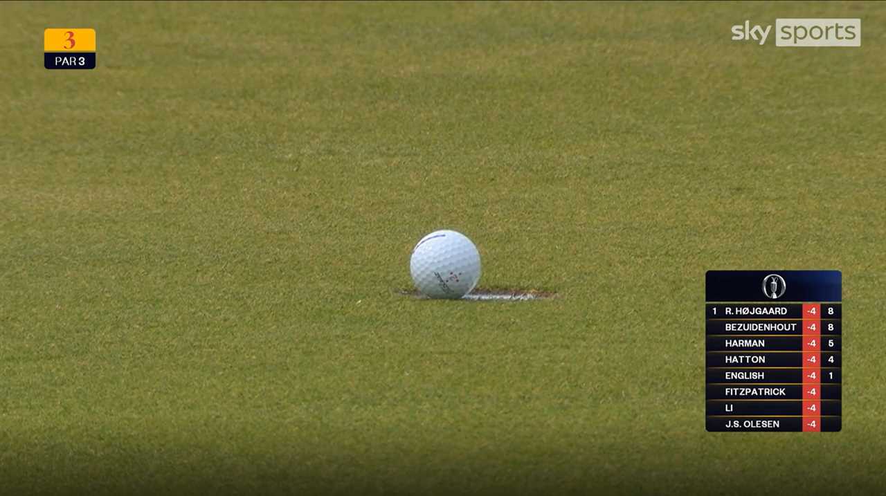 Golf ball near the hole on a putting green; leaderboard visible.