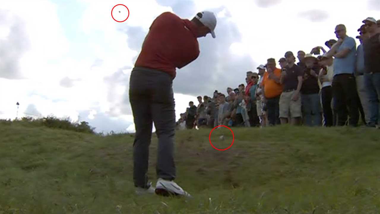 Golfer preparing to hit a golf ball with spectators watching.