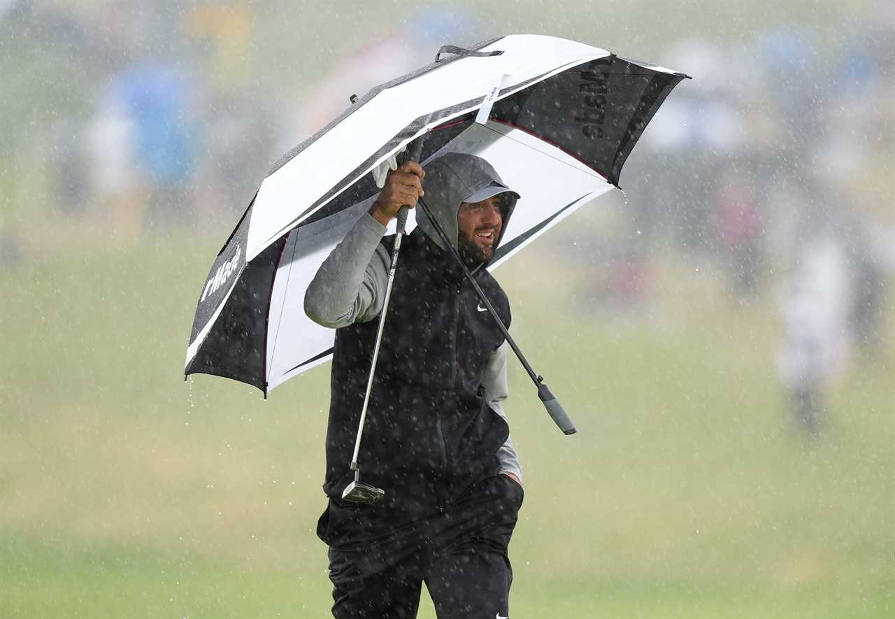 Golfer Scottie Scheffler under an umbrella in the rain.