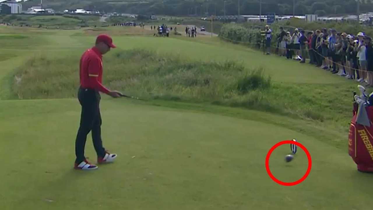 Golfer walking away after shot, golf ball on green.