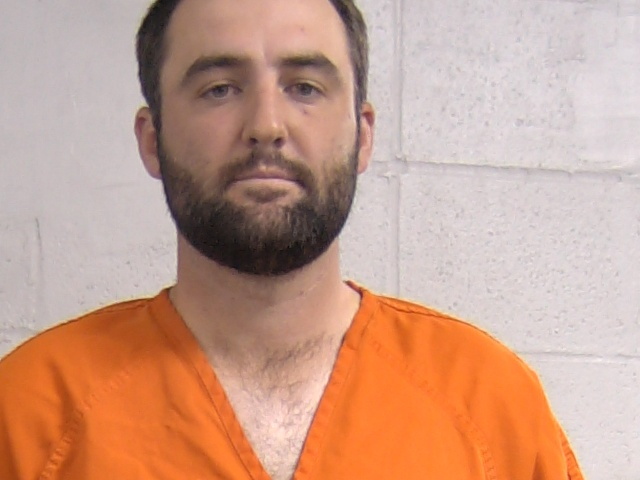 Mugshot of Scottie Scheffler in an orange jumpsuit.
