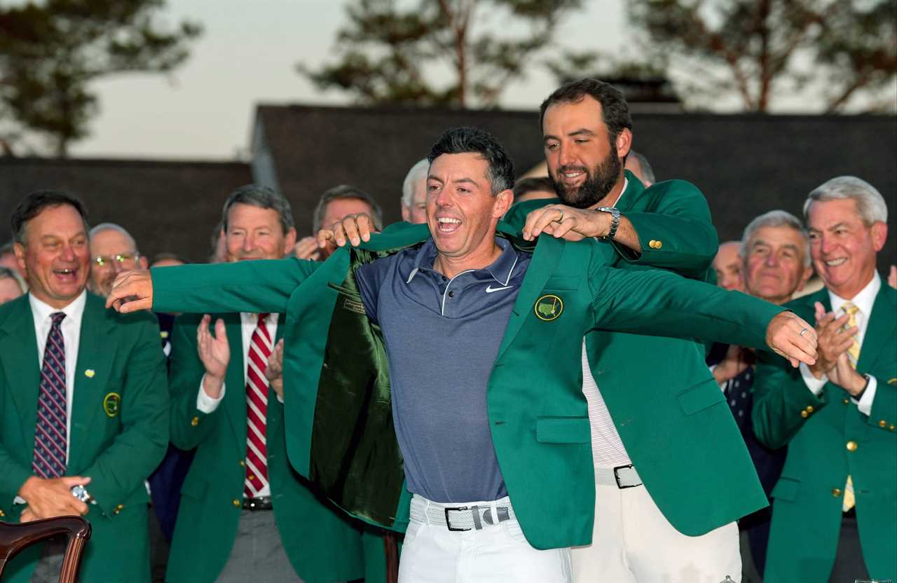 Scottie Scheffler placing the green jacket on Rory McIlroy at the Masters Tournament.