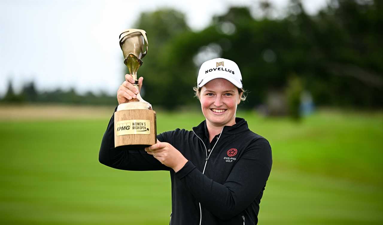 Golfer Lottie Woad kneeling with the KPMG Women's Irish Open trophy.