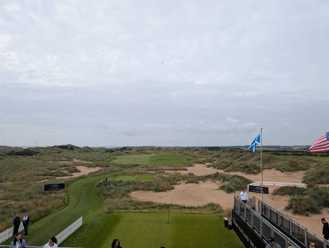Golf course with sand dunes, flags, and spectators.
